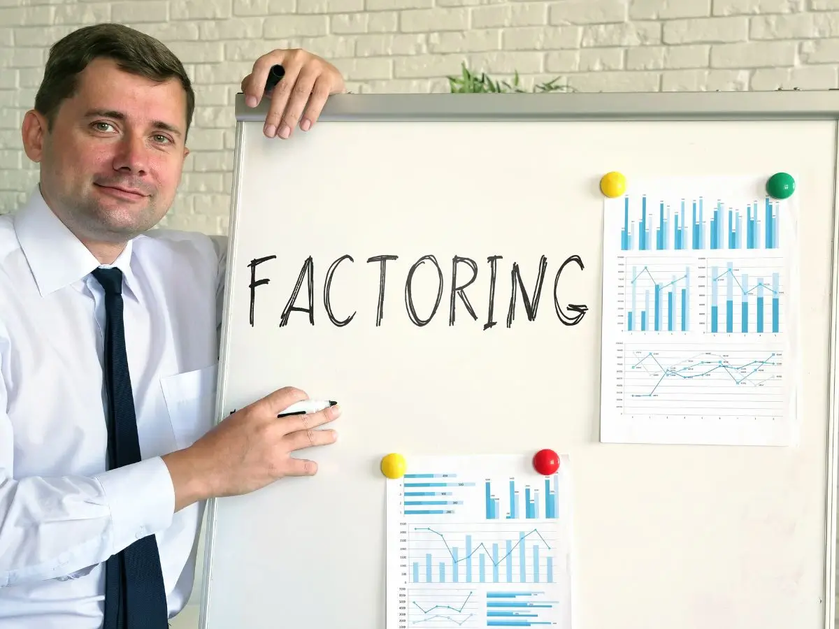 Uśmiechnięty mężczyzna w koszuli i krawacie prezentuje tablicę z napisem ‘Factoring’ oraz wykresami słupkowymi i liniowymi. Obraz ilustruje tematykę finansową i edukacyjną, podkreślając znaczenie faktoringu jako narzędzia wspierającego płynność firmy i obalającego popularne mity